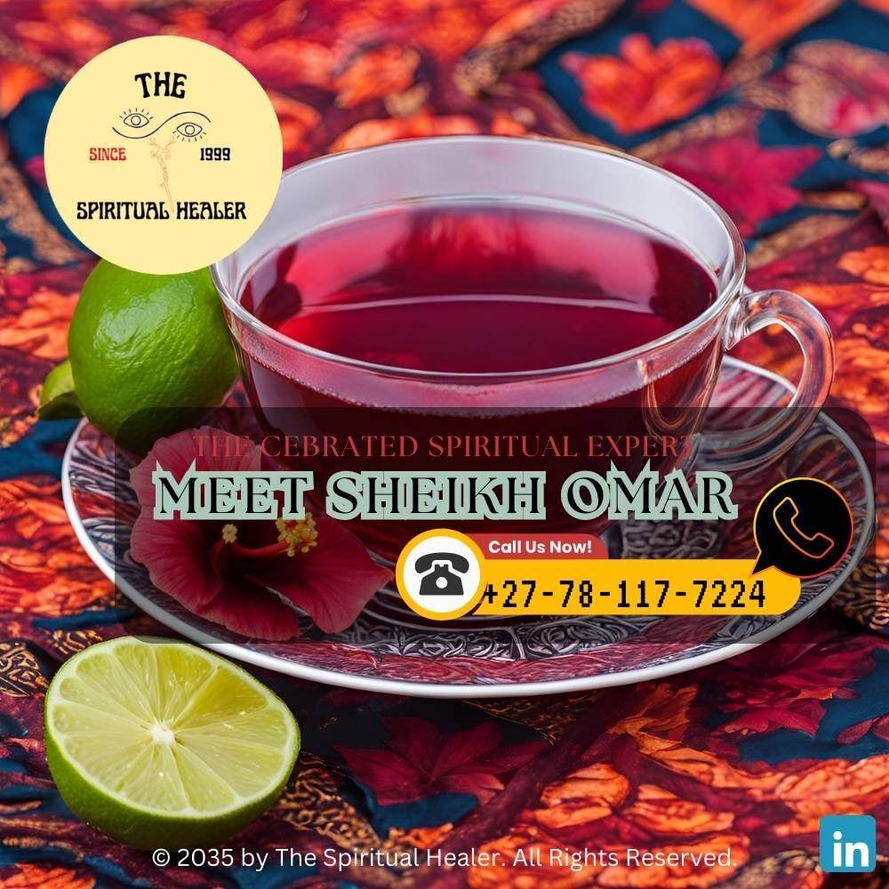 A cup of hibiscus tea with vibrant red hues, garnished with fresh petals and a slice of lime, set on a patterned African cloth.